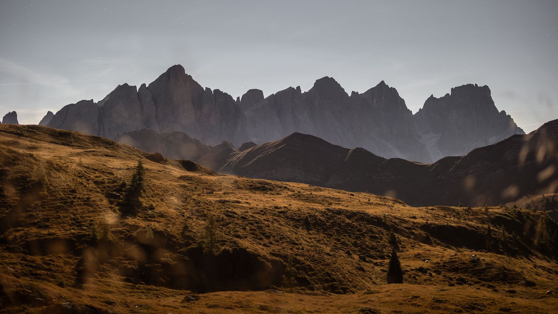 Golden meadows below a pale ridge at dusk