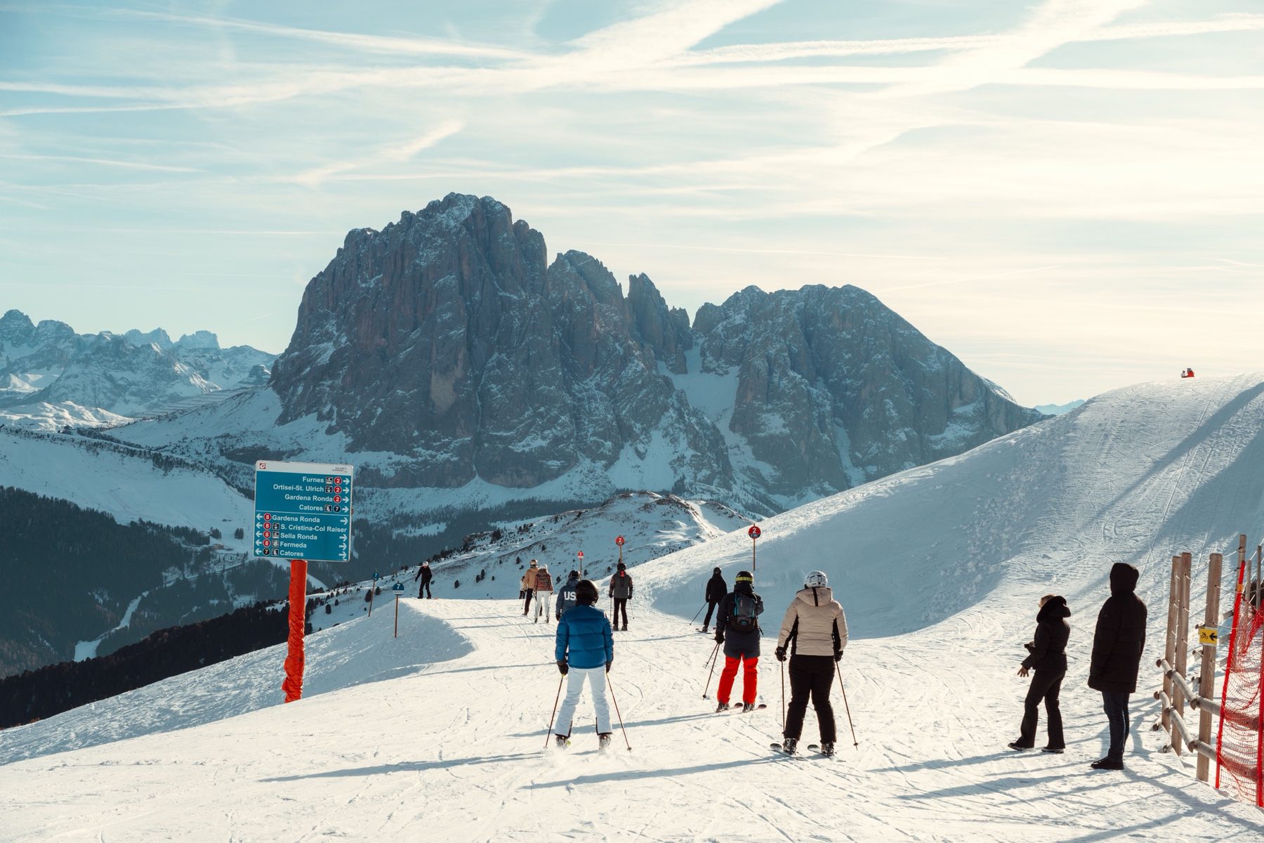 Skiers on a sunny piste at Seceda with the Sassolungo behind