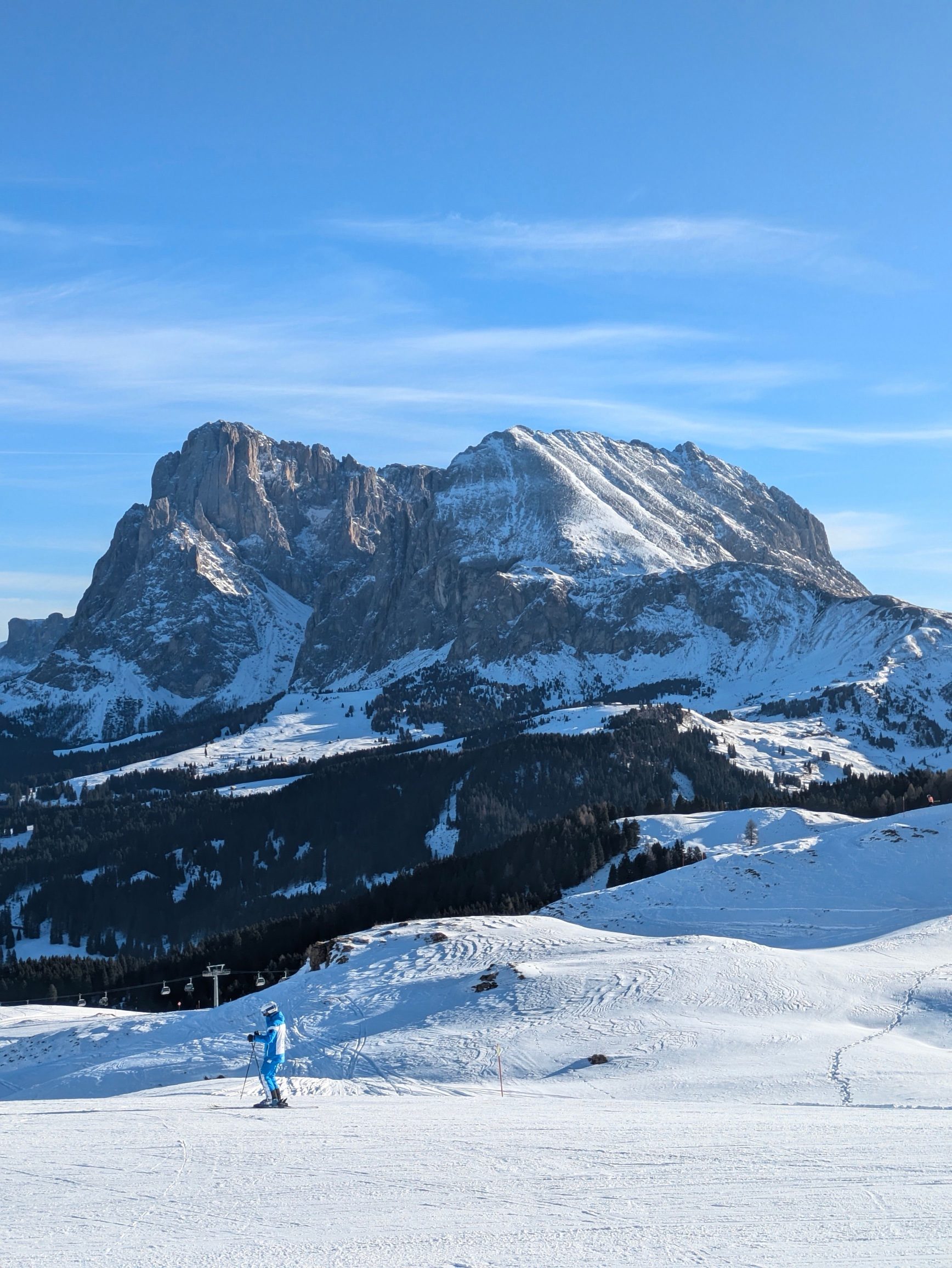 A skier on a wide, gentle slope on Alpe di Siusi with the Sassolungo behind